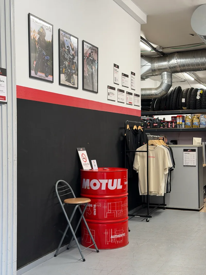 Recepción del taller con el mostrador, carteles de motos en la pared y un bidón de Motul
